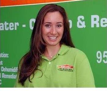 Female employee smiling in front of a green SERVPRO truck.